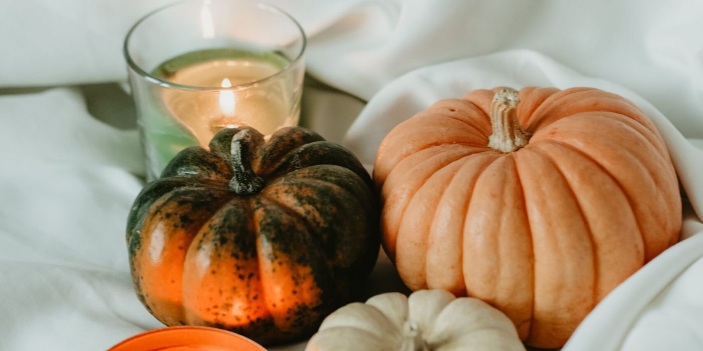 Pumpkins sitting on a sheet with a candle lit next to it.