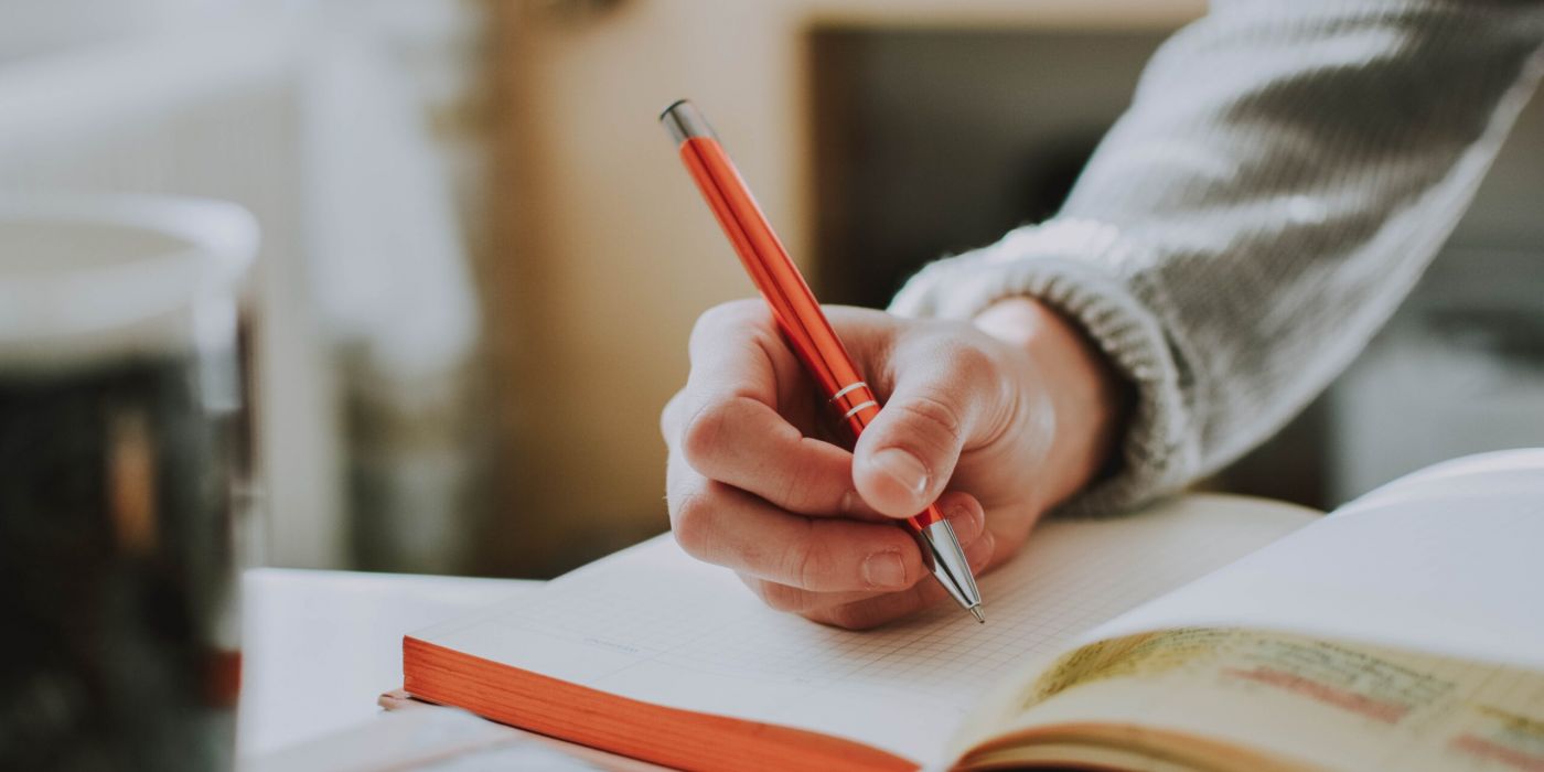Person holding a pen about a notebook, practicing good study habits.