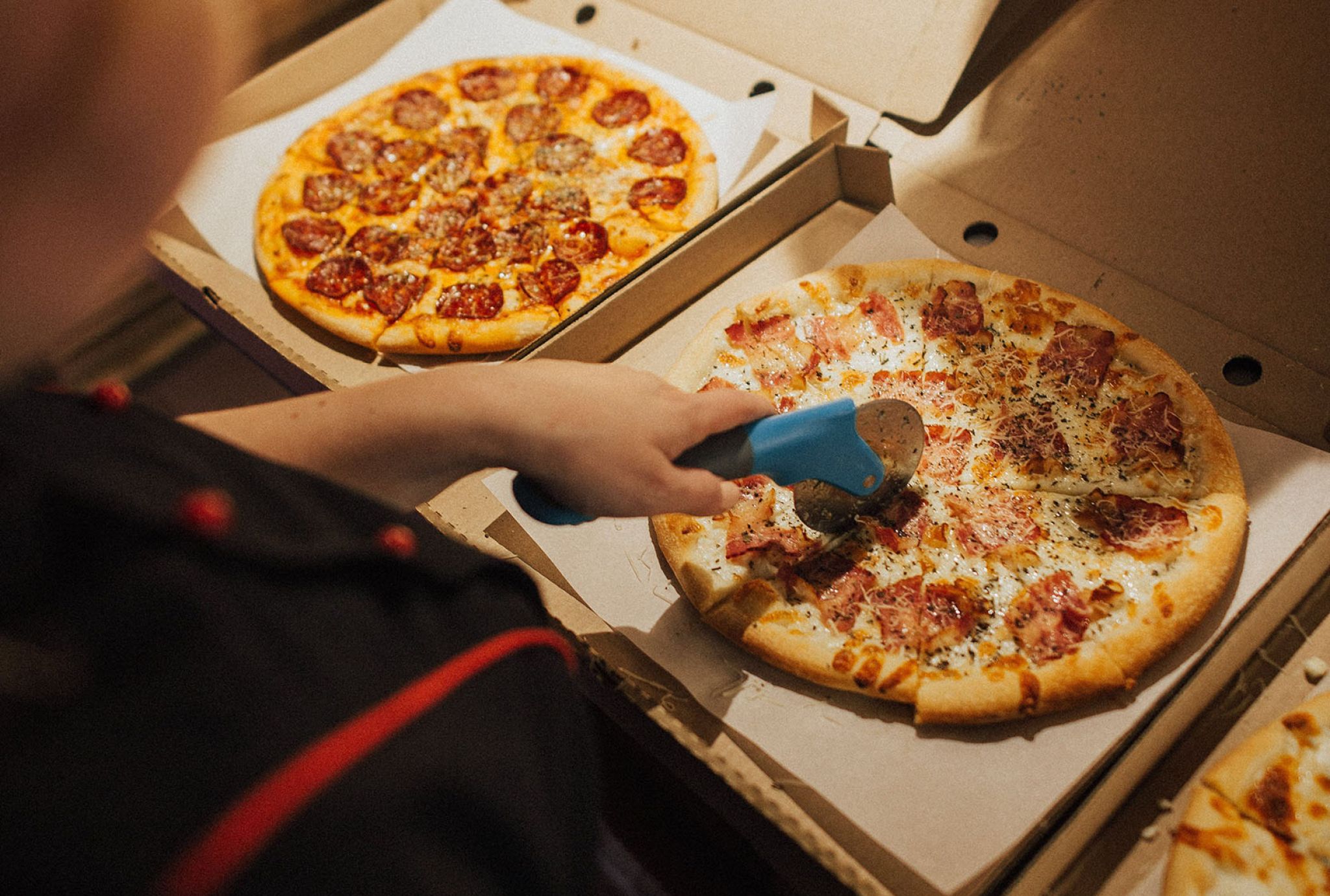 person cutting a pizza with a pizza cutter