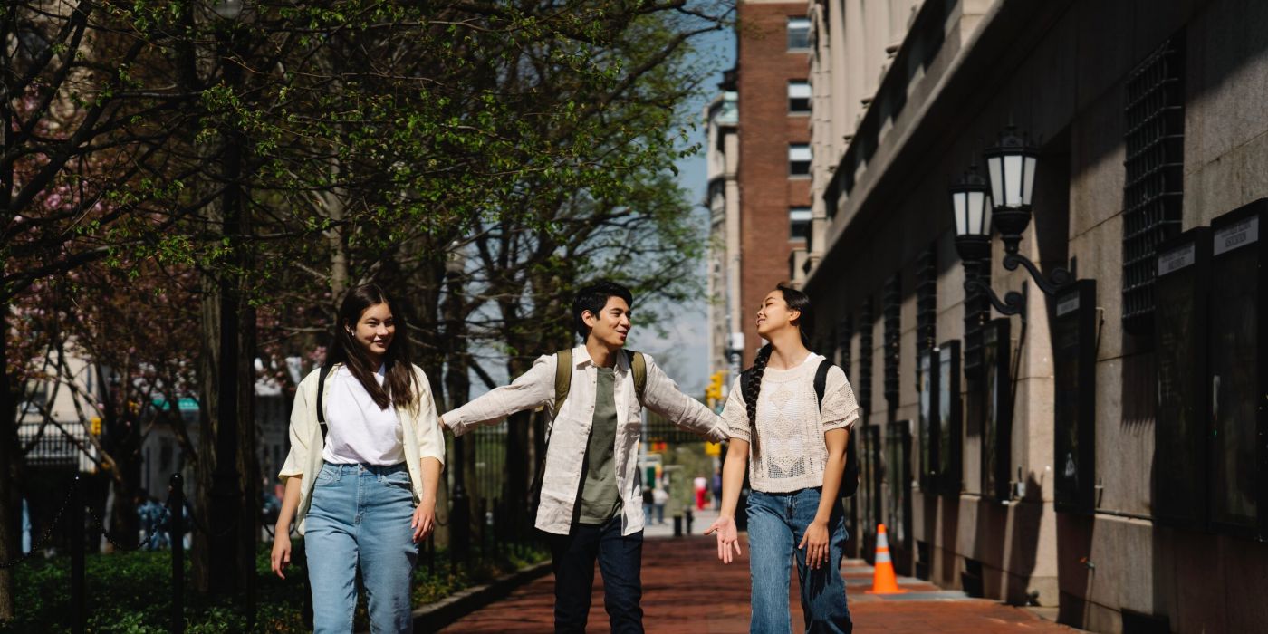 Tres personas de pie hablando, en edad universitaria.