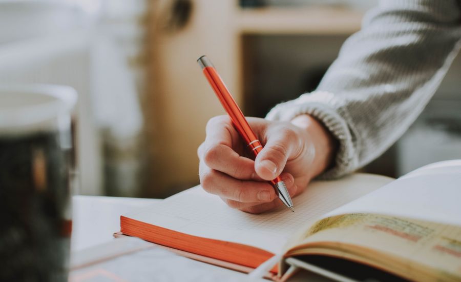 Person holding a pen about a notebook, practicing good study habits.